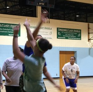 Lady Angels Captain Jeaneen White looks on as team members vie for the basketball