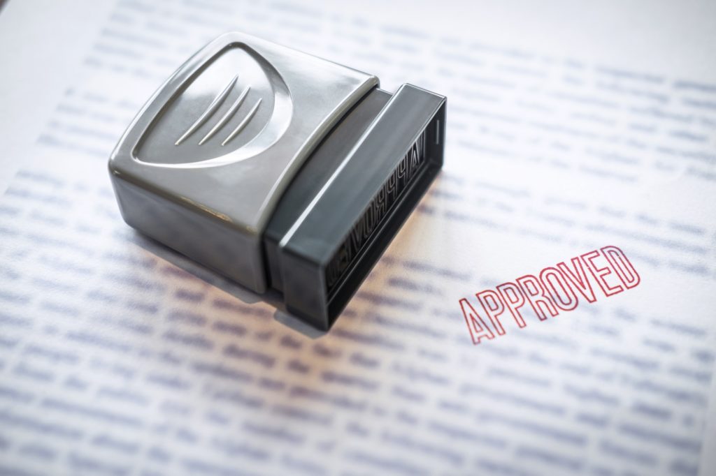 Close up stamp on paper document to approve business investment contract agreement